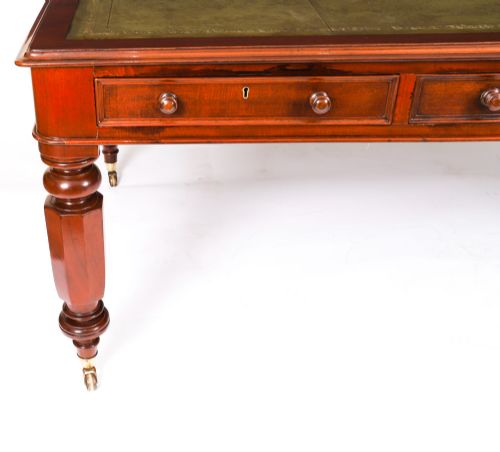 fig 2. A nineteenth-century mahogany partners writing table featuring a green leather inset surface, six drawers with turned knobs, and octagonal turned legs on brass castors.