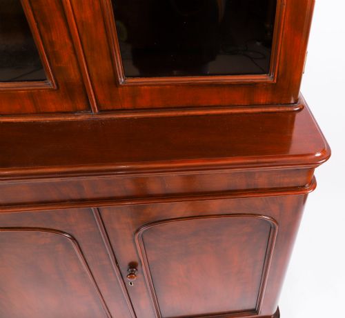 fig 6. A large 19th-century Victorian flame mahogany library bookcase featuring a glazed three-door upper section filled with books above a solid three-door cupboard base.