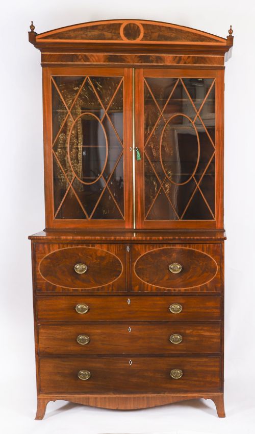 fig 2. A George III flame mahogany secretaire bookcase featuring an arched pediment, astragal glazed doors, and lower drawers on bracket feet.