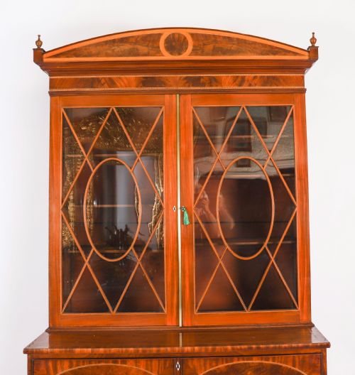 fig 3. A George III flame mahogany secretaire bookcase featuring an arched pediment, astragal glazed doors, and lower drawers on bracket feet.