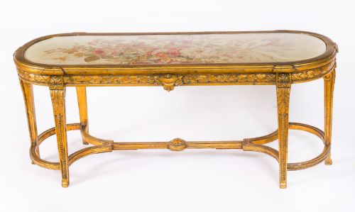 fig 1. An early 20th-century oval French Louis XVI style giltwood low table featuring an inlaid tapestry top under glass and carved legs connected by a stretcher.