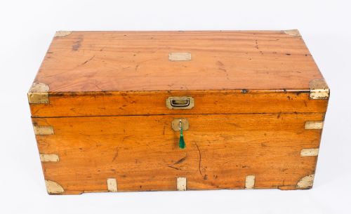 fig 1. A rectangular 19th-century warm brown camphorwood military campaign trunk featuring flush brass corner brackets, protective metal straps, side drop handles, and a central brass keyhole escutcheon.
