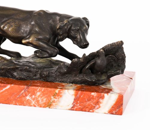 fig 3. A dark brown patinated bronze sculpture of a hunting dog stalking prey, mounted on a rectangular red and white veined marble base.