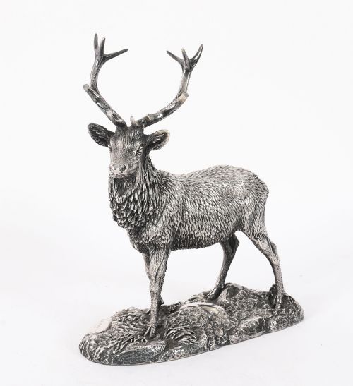 fig 1. A detailed sterling silver sculpture of a standing stag with branching antlers positioned on a textured rocky ground base.