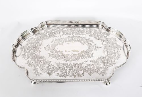 fig 1. An Edwardian silver-plated gallery tray featuring a pierced rim, engraved foliate scrollwork, twin handles, and ball feet.
