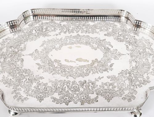 fig 2. An Edwardian silver-plated gallery tray featuring a pierced rim, engraved foliate scrollwork, twin handles, and ball feet.