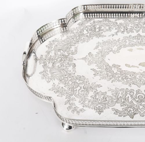 fig 3. An Edwardian silver-plated gallery tray featuring a pierced rim, engraved foliate scrollwork, twin handles, and ball feet.