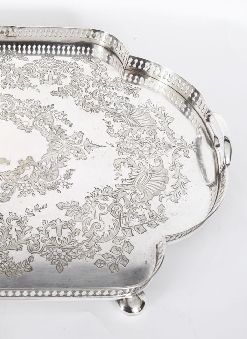 fig 6. An Edwardian silver-plated gallery tray featuring a pierced rim, engraved foliate scrollwork, twin handles, and ball feet.