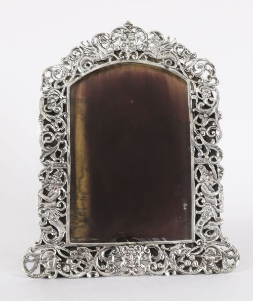 fig 1. An antique sterling silver photo frame featuring openwork scrollwork detailing and a dark wooden easel back.