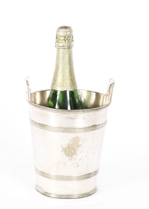 fig 1. An Art Deco silver-plated champagne cooler featuring angular raised handles, horizontal reeded bands, and an engraved circular crest.