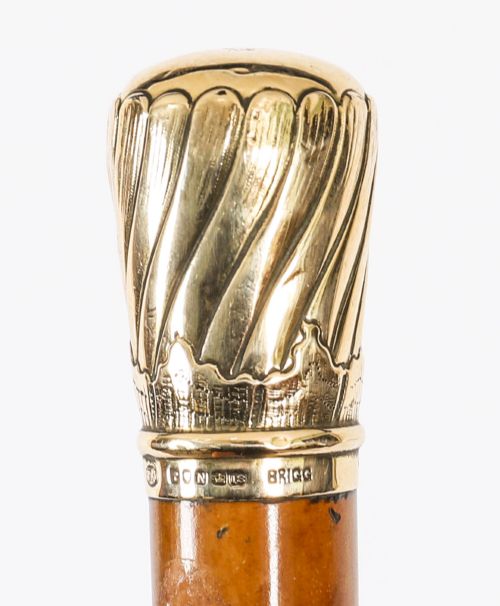 fig 1. A straight polished wooden walking cane featuring a decorated 18ct gold pommel handle and a metal ferrule tip at the base.