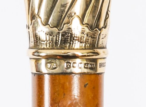A straight polished wooden walking cane featuring a decorated 18ct gold pommel handle and a metal ferrule tip at the base. View VI