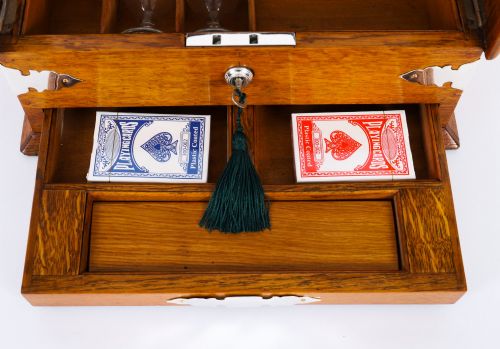fig 8. An antique blonde oak tantalus featuring three square cut-glass decanters set against a mirror back, decorative silver-plated corner mounts, and a lower drawer with a key.