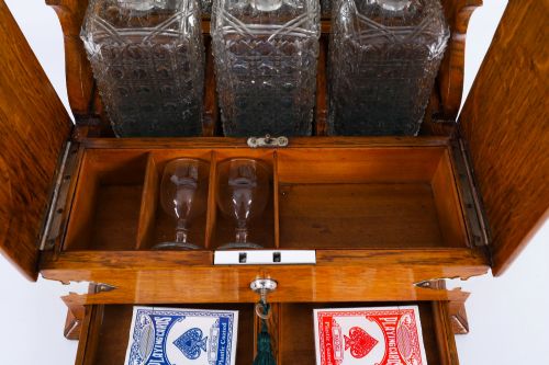 fig 9. An antique blonde oak tantalus featuring three square cut-glass decanters set against a mirror back, decorative silver-plated corner mounts, and a lower drawer with a key.