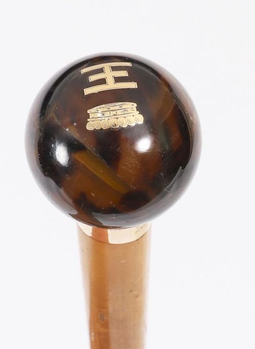 fig 1. An antique Victorian wooden walking stick featuring a dark spherical pommel, an 18ct gold collar band, and a tapered brown shaft.