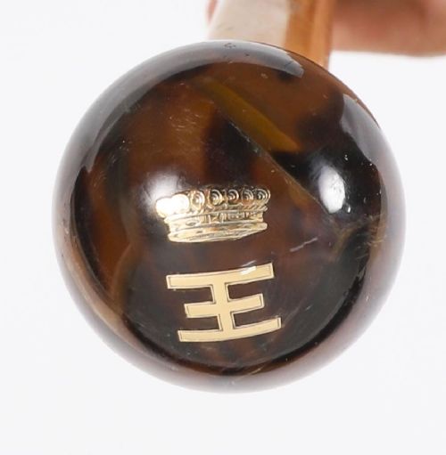 fig 2. An antique Victorian wooden walking stick featuring a dark spherical pommel, an 18ct gold collar band, and a tapered brown shaft.