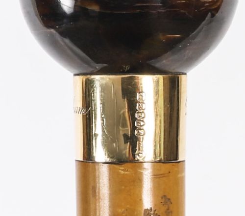 An antique Victorian wooden walking stick featuring a dark spherical pommel, an 18ct gold collar band, and a tapered brown shaft. View X