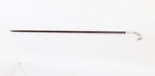 fig 1. An antique French walking cane featuring a hand-hammered crook-shaped silver handle mounted on a dark wooden shaft.