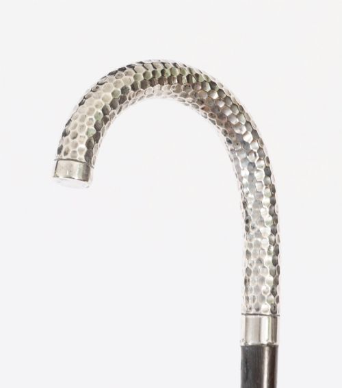 fig 2. An antique French walking cane featuring a hand-hammered crook-shaped silver handle mounted on a dark wooden shaft.