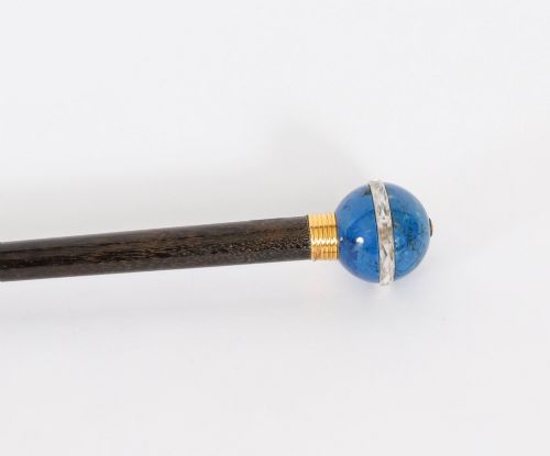 fig 3. An Edwardian walking cane featuring a spherical lapis lazuli pommel accented with a faceted crystal band and a ribbed gold collar on a dark hardwood shaft.