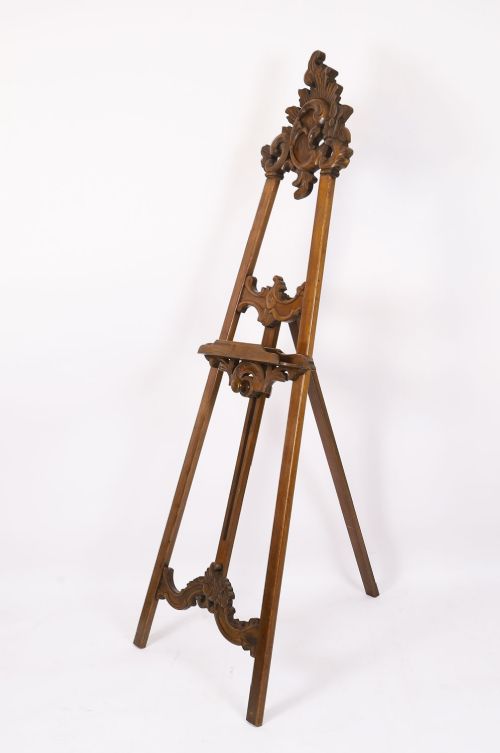 fig 2. A 19th-century carved walnut artist easel featuring an ornate Rococo Revival scrollwork crest and an adjustable ledge on a tripod frame.