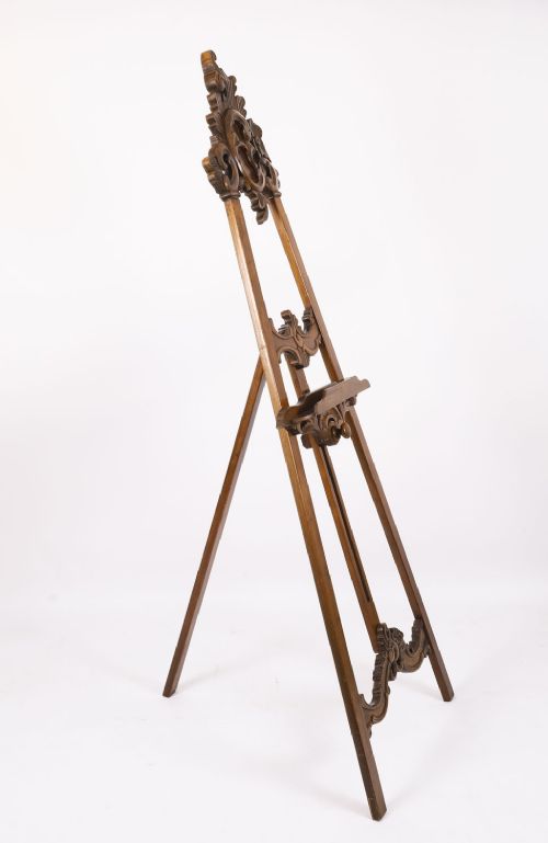 A 19th-century carved walnut artist easel featuring an ornate Rococo Revival scrollwork crest and an adjustable ledge on a tripod frame. View XI