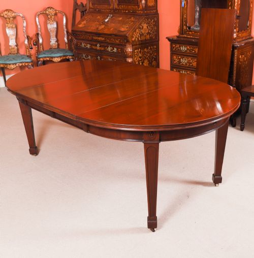 fig 4. An antique Victorian oval extending dining table crafted from flame mahogany with tapered legs on brass castors.