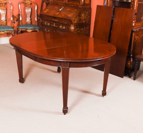 fig 5. An antique Victorian oval extending dining table crafted from flame mahogany with tapered legs on brass castors.
