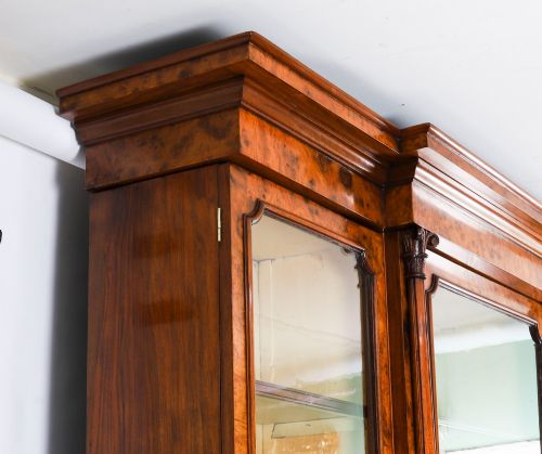 fig 4. A mid-19th-century Victorian burr walnut breakfront bookcase featuring three upper glazed doors, turned pilasters, and three lower panelled cupboard doors.