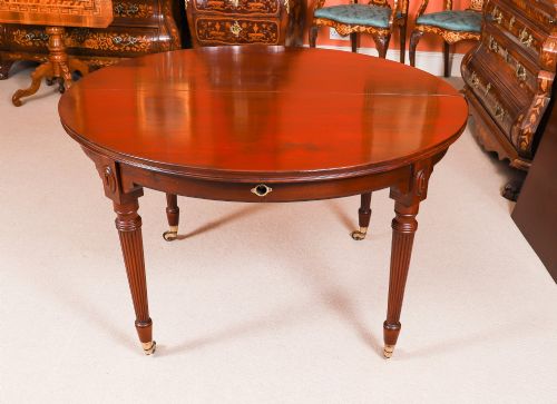 fig 9. An antique Victorian flame mahogany extending dining table with fluted tapering legs set on brass castors.