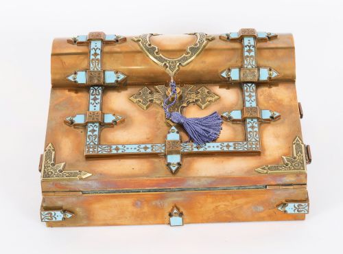 fig 2. A Victorian gilt brass and turquoise champleve enamel writing slope featuring a domed upper compartment, a sloped front lid, and a key with a purple tassel in the lock.