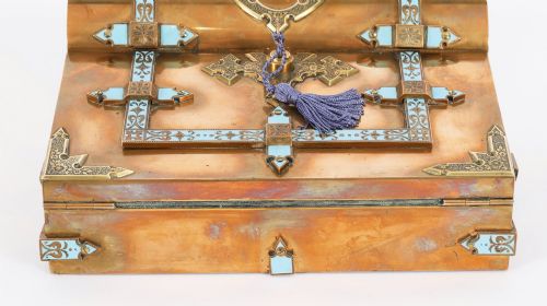 fig 3. A Victorian gilt brass and turquoise champleve enamel writing slope featuring a domed upper compartment, a sloped front lid, and a key with a purple tassel in the lock.
