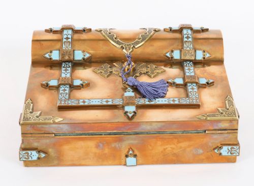fig 4. A Victorian gilt brass and turquoise champleve enamel writing slope featuring a domed upper compartment, a sloped front lid, and a key with a purple tassel in the lock.