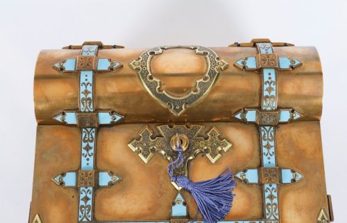 fig 5. A Victorian gilt brass and turquoise champleve enamel writing slope featuring a domed upper compartment, a sloped front lid, and a key with a purple tassel in the lock.