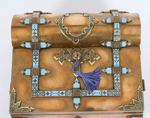 fig 6. A Victorian gilt brass and turquoise champleve enamel writing slope featuring a domed upper compartment, a sloped front lid, and a key with a purple tassel in the lock.