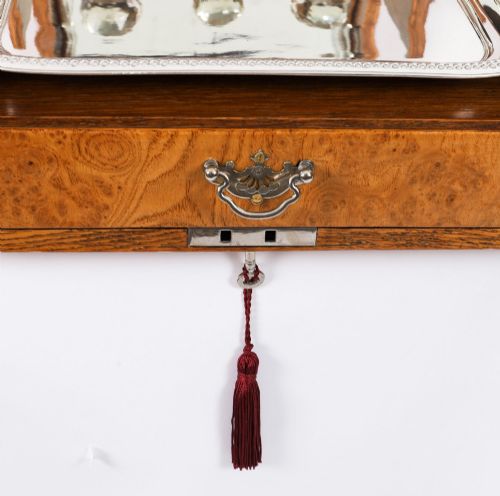 fig 6. A 19th-century Victorian figured oak three-bottle tantalus open to reveal three cut glass decanters, a fitted cribbage board, and a drop-front drawer containing a silver-plated tray and playing cards.