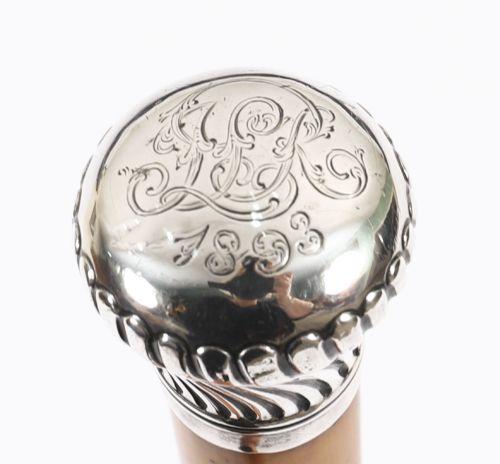 fig 3. Victorian walking cane featuring an engraved sterling silver pommel with spiralled fluting mounted on a light wood shaft.