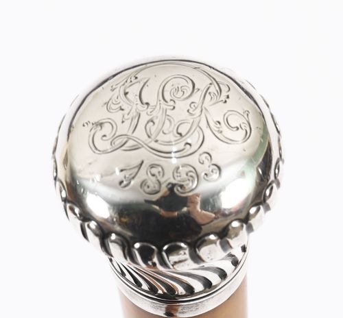 fig 6. Victorian walking cane featuring an engraved sterling silver pommel with spiralled fluting mounted on a light wood shaft.