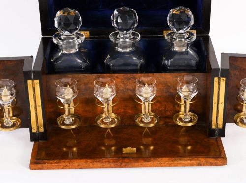fig 3. An open and closed 19th-century Victorian burr walnut tantalus box containing three cut crystal decanters, brass-mounted liqueur glasses, and a deep blue velvet lining.