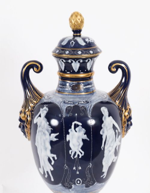 fig 4. A pair of cobalt blue and white porcelain lidded vases featuring classical figures, scrolling handles, and gilded finials.