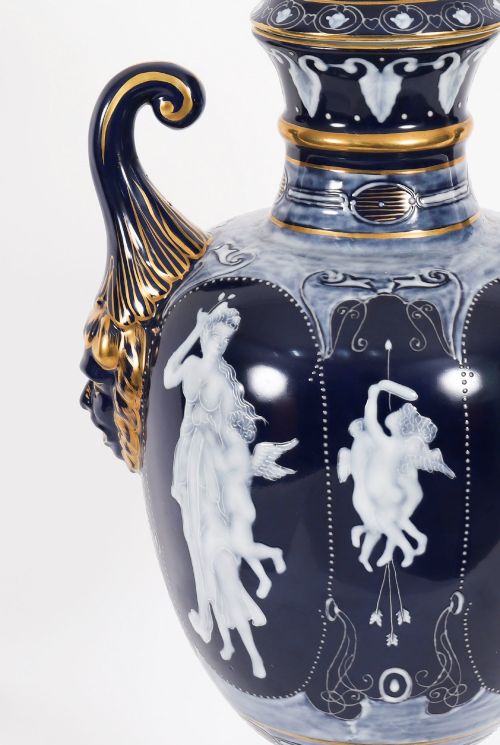 fig 6. A pair of cobalt blue and white porcelain lidded vases featuring classical figures, scrolling handles, and gilded finials.