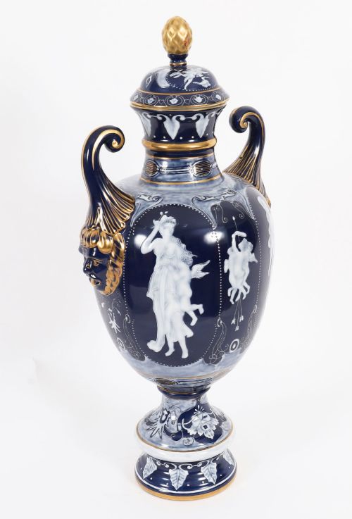 fig 7. A pair of cobalt blue and white porcelain lidded vases featuring classical figures, scrolling handles, and gilded finials.