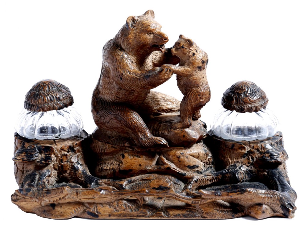 A 19th-century carved wood Black Forest inkstand featuring a mother bear and cub sitting on a naturalistic log base between two clear glass inkwells.
