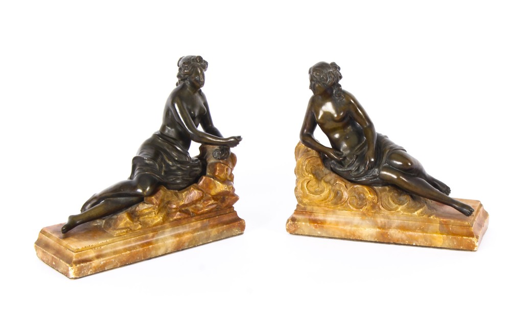 A pair of 19th-century dark bronze sculptures depicting semi-nude classical reclining female figures set upon carved yellow marble bases.