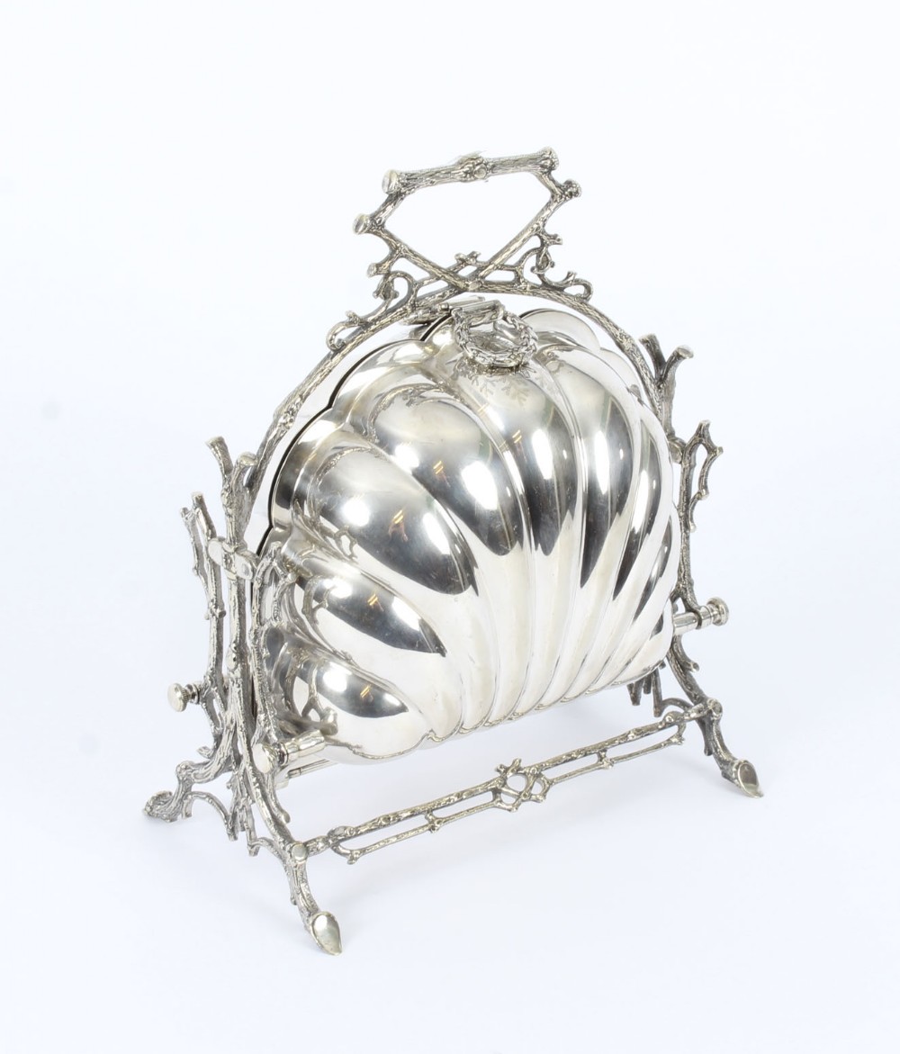 An antique Victorian silver-plated folding biscuit box shaped like a double scallop shell suspended in a twig-form metal frame.
