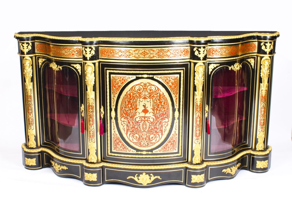 A nineteenth-century ebonised serpentine credenza featuring brass and tortoiseshell Boulle marquetry, cast gilt-bronze ormolu mounts, a central panelled door, and glass display sides.