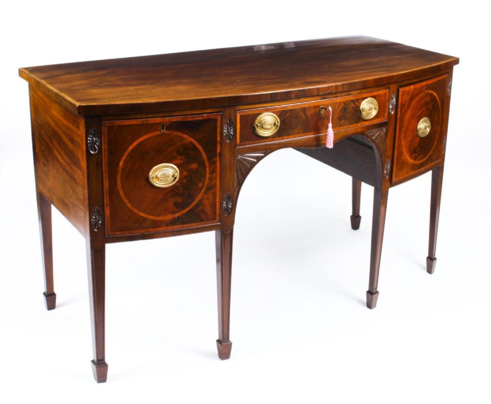 An 18th-century George III flame mahogany sideboard featuring circular inlaid panels, brass ring handles, and square tapered legs.