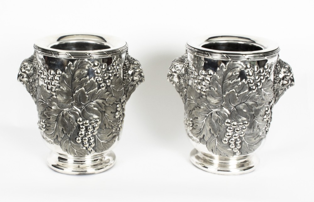 A pair of nineteenth-century silver-plated wine coolers featuring relief grapevines and side handles on pedestal bases.