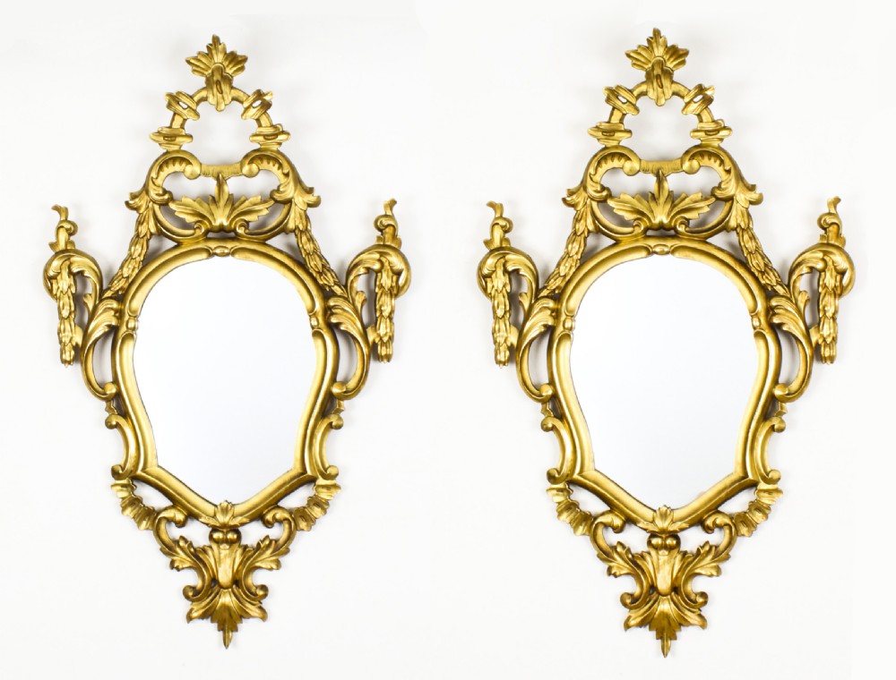 A matching pair of 19th-century Florentine Rococo carved giltwood wall mirror frames featuring intricate acanthus leaf cresting and scrollwork.