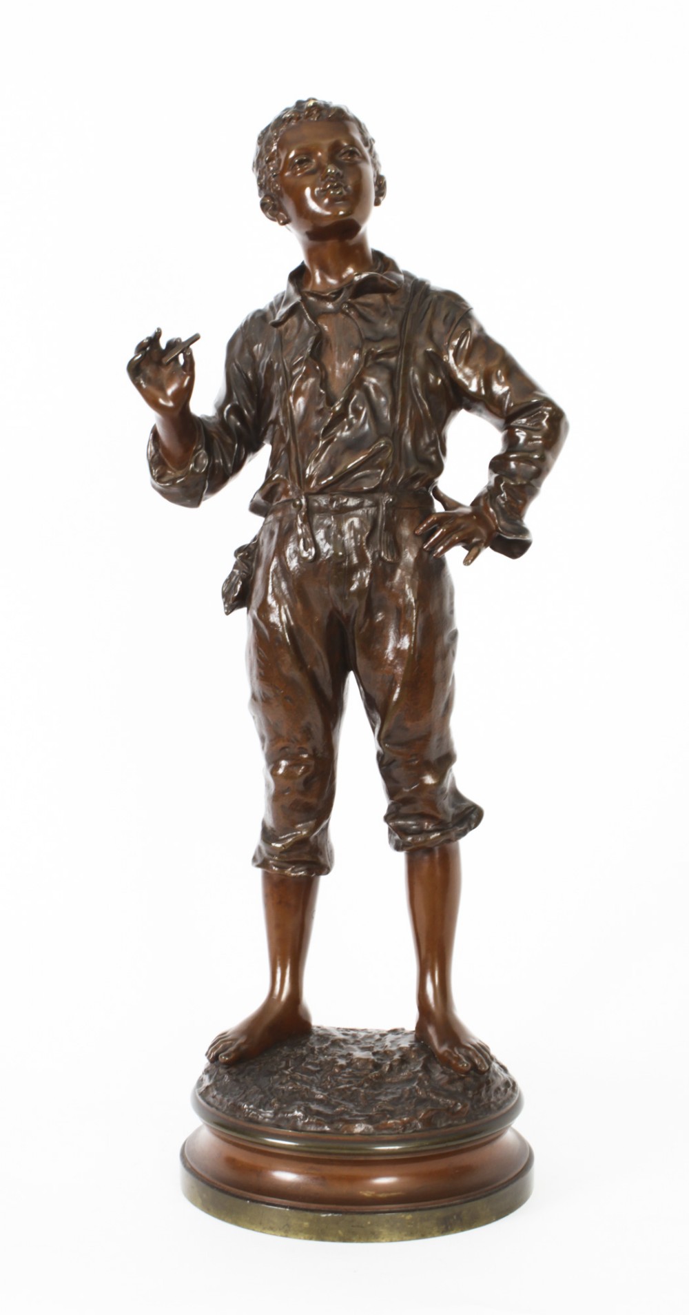 A 19th-century French bronze sculpture depicting a standing young boy in working clothing on a circular base.
